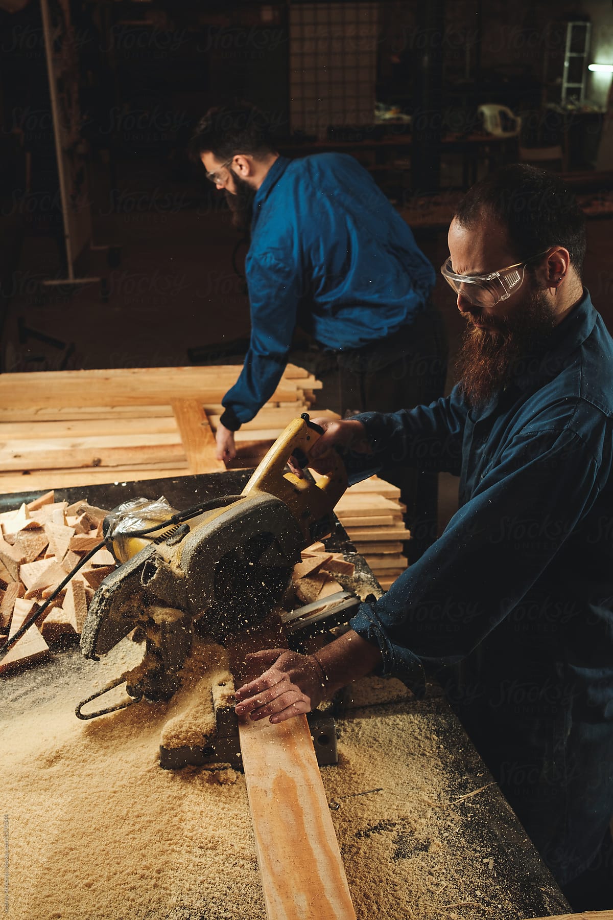 Two carpenters working in workshop/sawmil with wood.