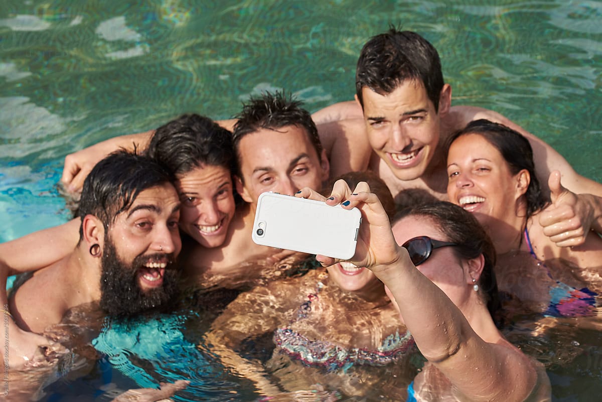 Happy friends taking selfie on cell in pool
