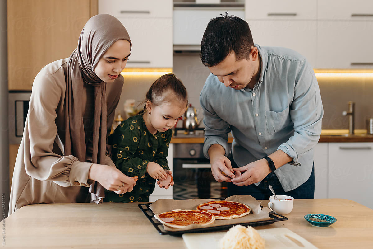 Muslim parents with kid preparing pizza together