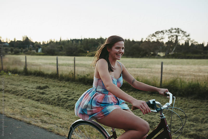 Young happy caucasian girl riding cruiser bike on country road