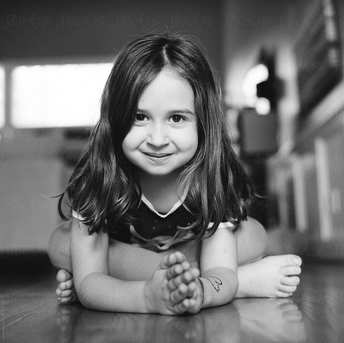 Cute Young Girl Sitting On The Floor Leaning Toward The Camera By 