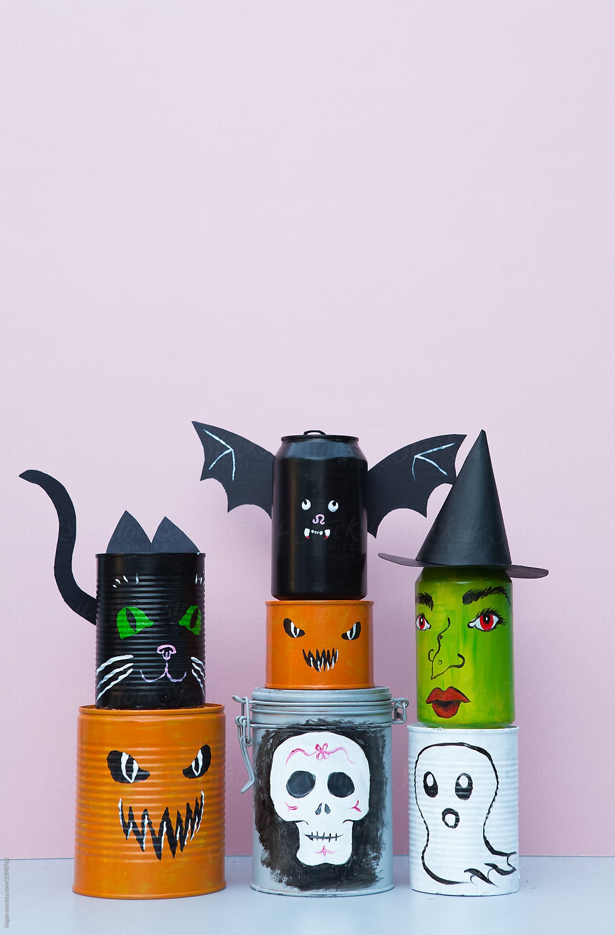 Cans decorated with Halloween characters including a witch, bat, ghost and jack-o-lantern