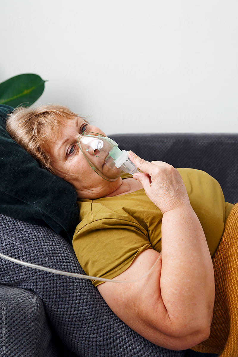 Woman in oxygen mask on couch