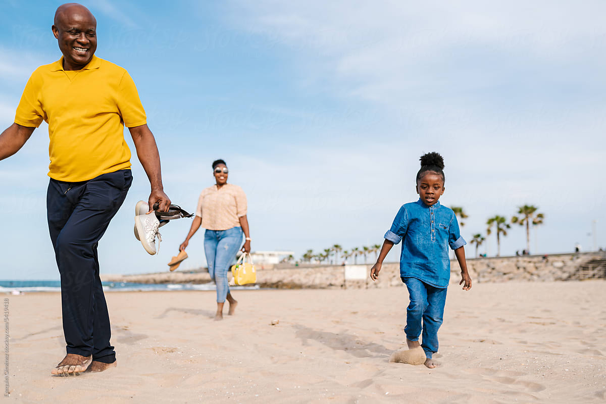 Black family walking on sandy beach