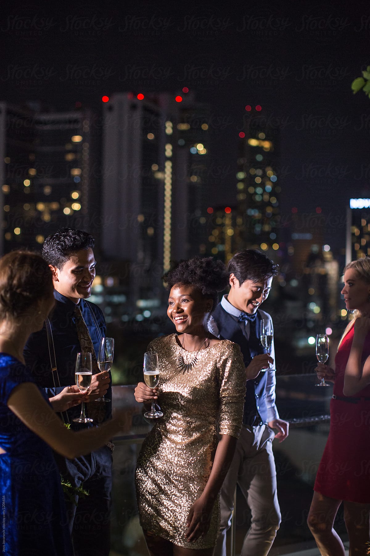 Woman in sequin dress having fun with friends on rooftop