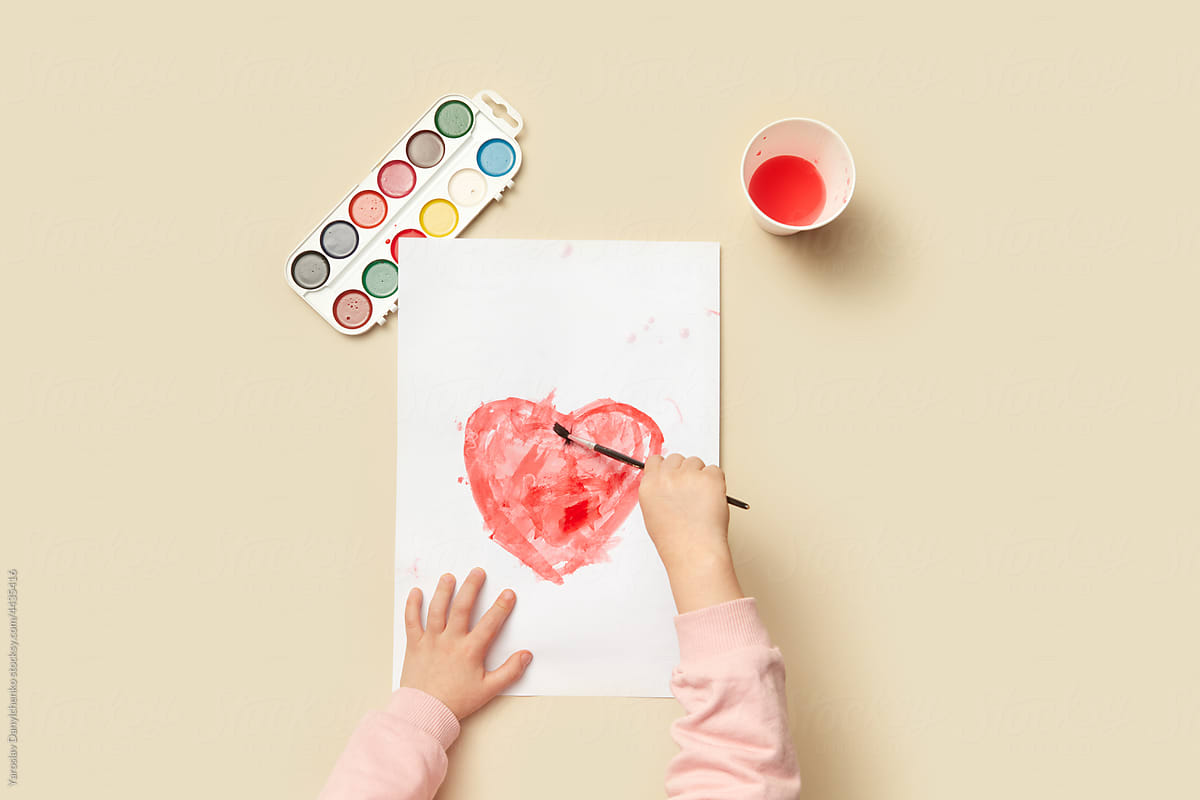 Little child painting heart on paper greeting card