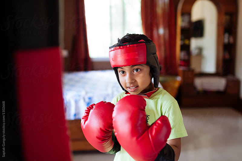 Child wearing boxing gloves punching punch bag