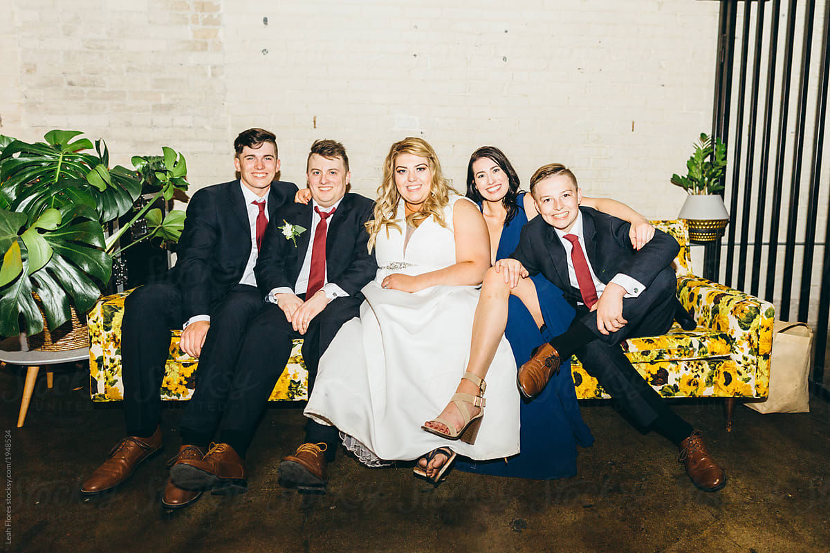 Bride And Groom Sitting On Retro Couch With The Brides Siblings By Stocksy Contributor Leah 