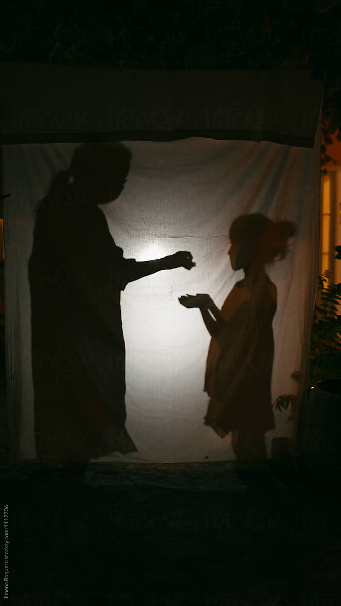 Silhouette of kid and adult behind backlit hanging clot