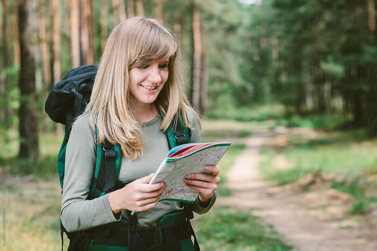 Woman looking at map hiking in summer forest
