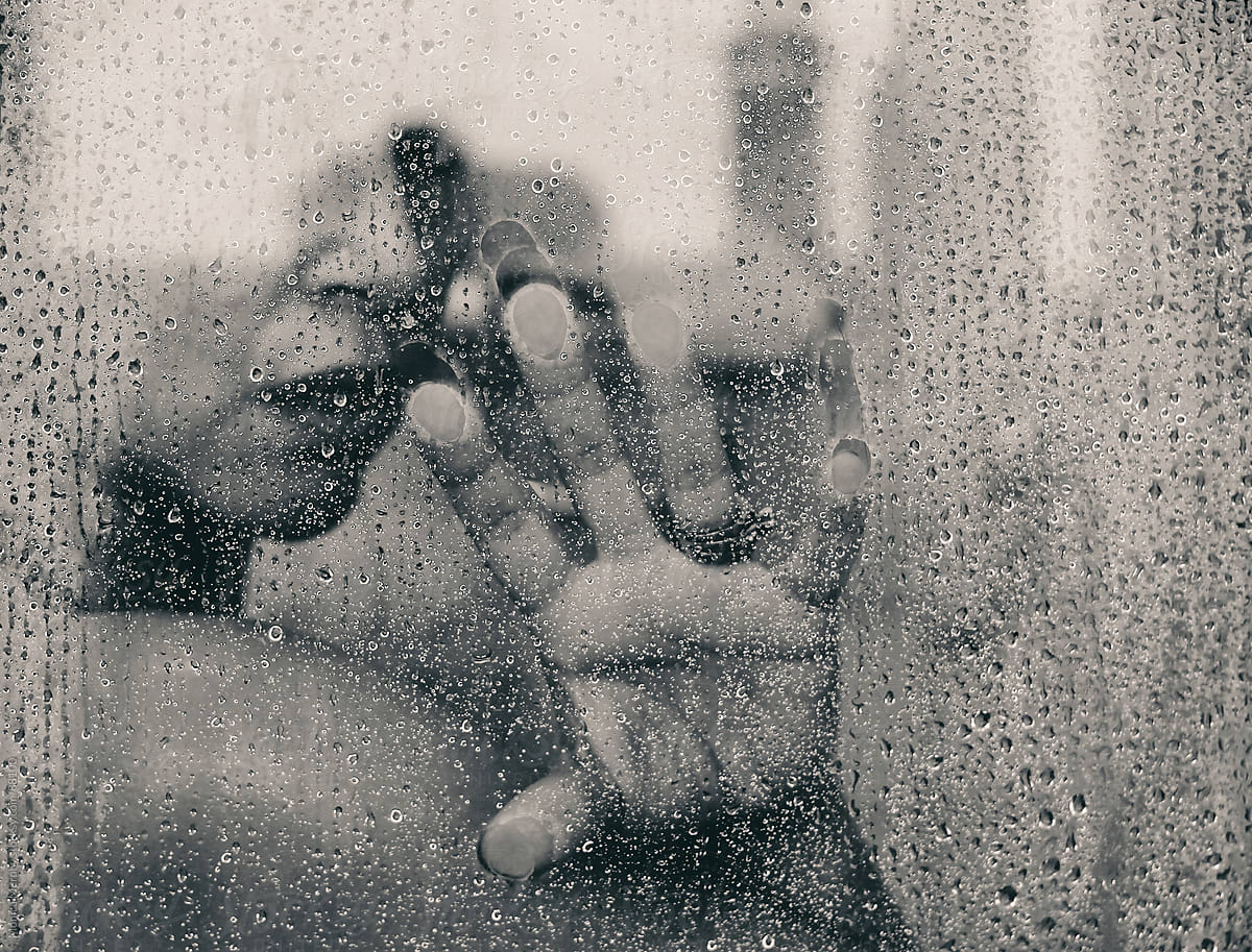 Woman looking out of hot shower, hand on glass