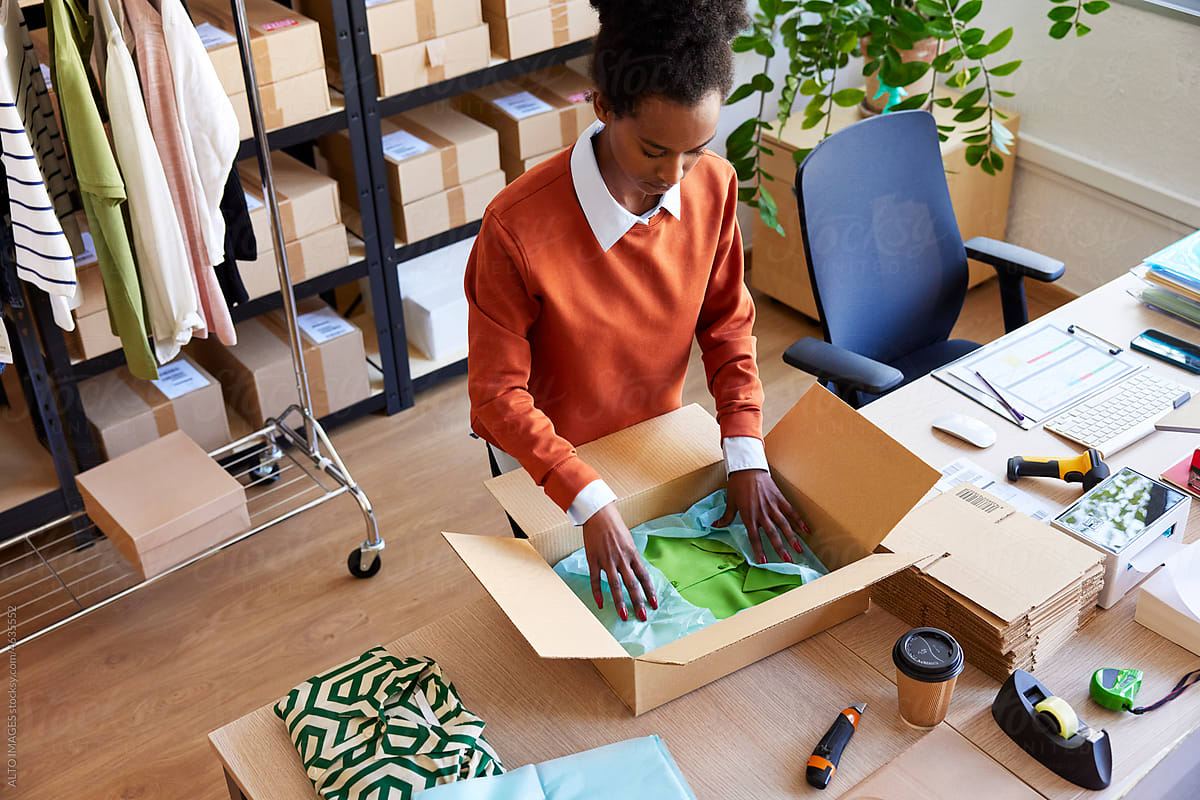 Black woman packing garment in logistic office
