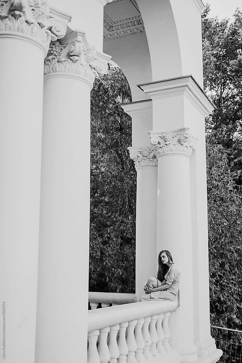 Black and white portrait of pretty female sitting on balustrade
