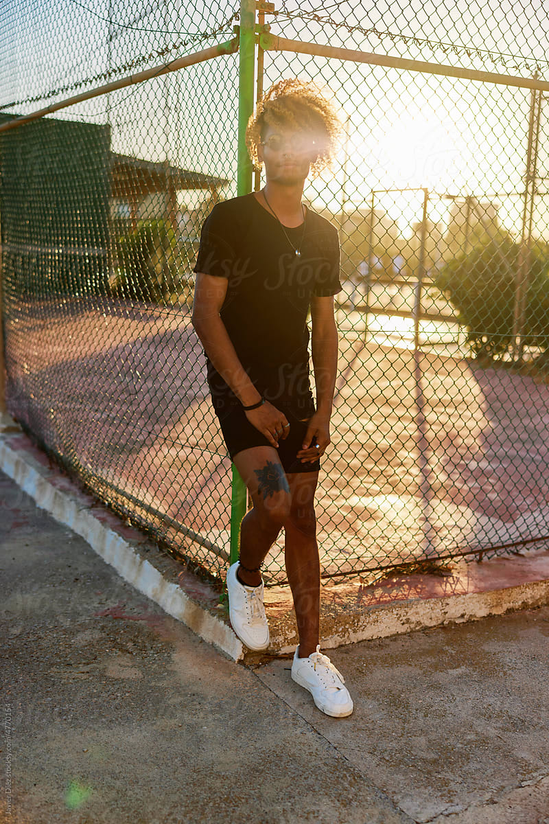 Young man standing on street at sunset