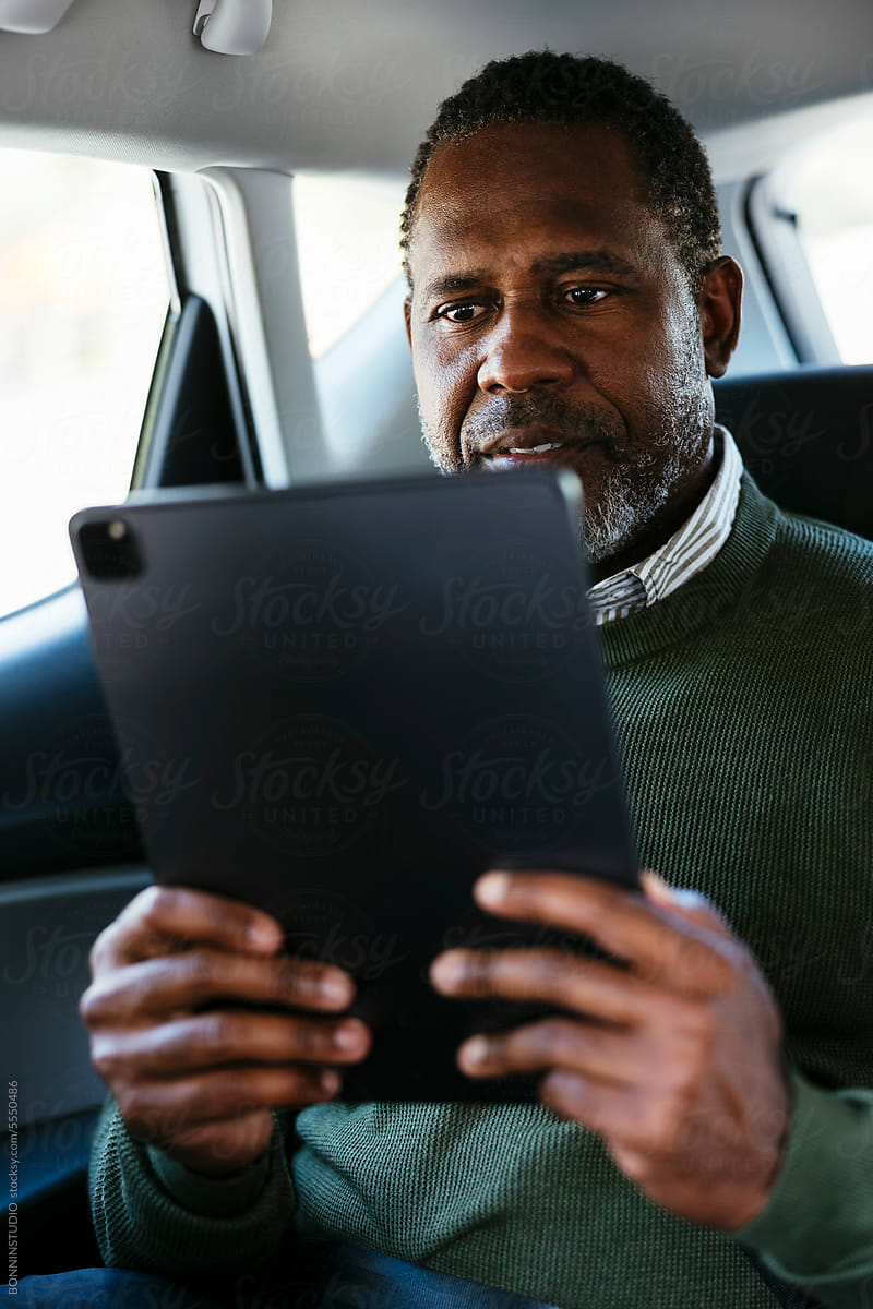 Serious mature man using tablet in car