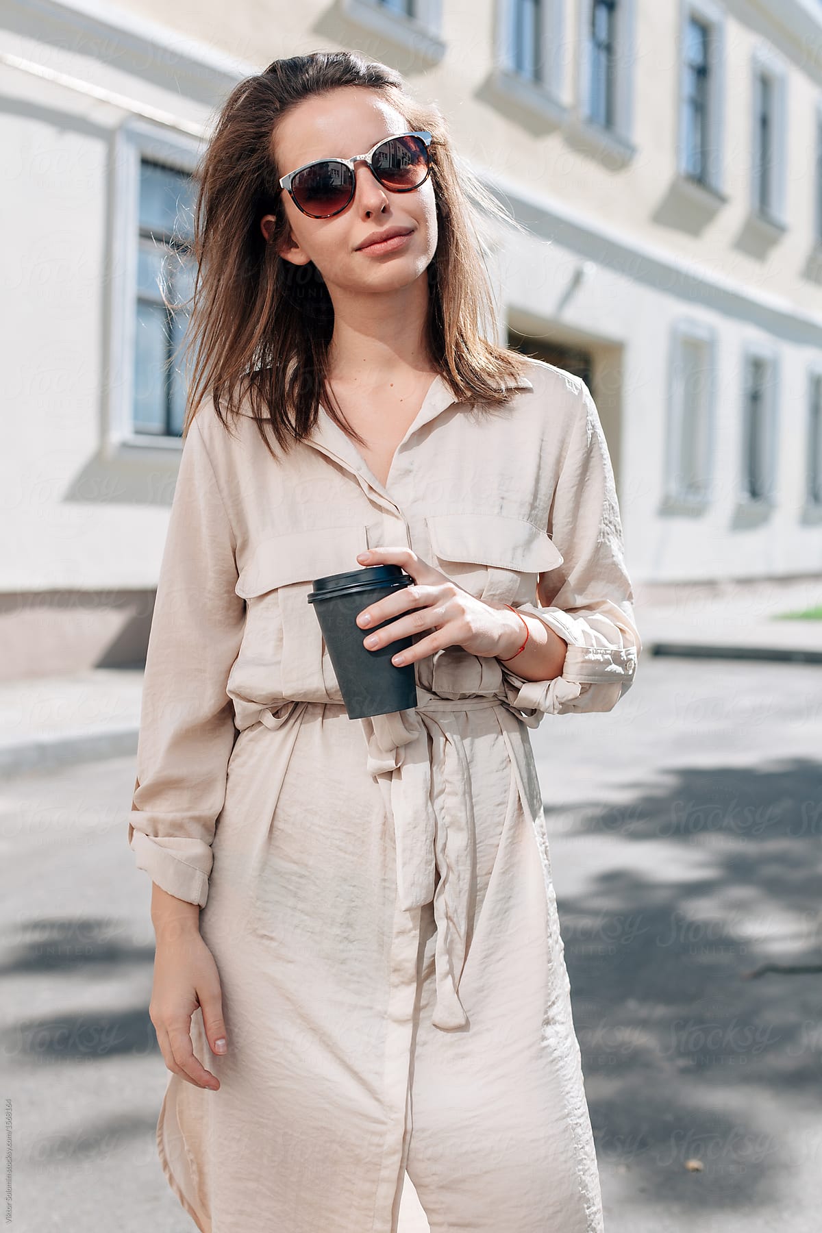 Closeup portrait of pretty sensual woman having cup of coffee in hands standing on the street