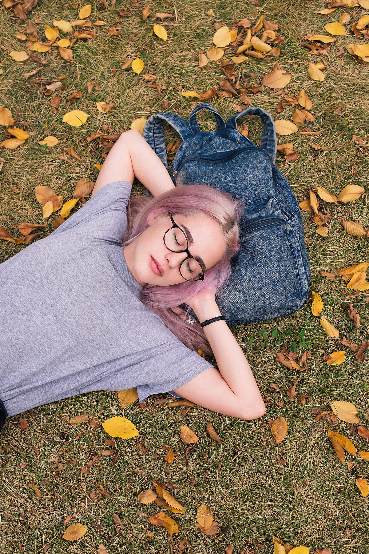 Pretty pink-haired woman in glasses asleep in park