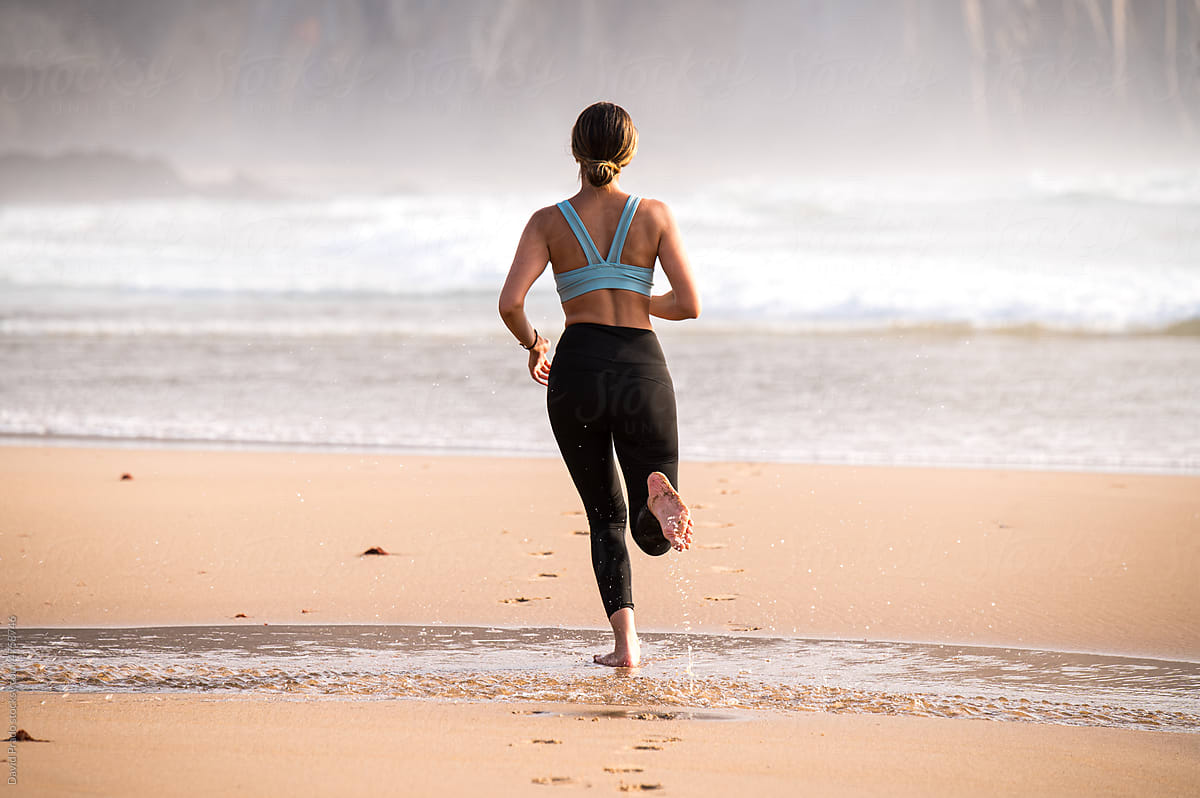 Faceless woman running on coast near sea