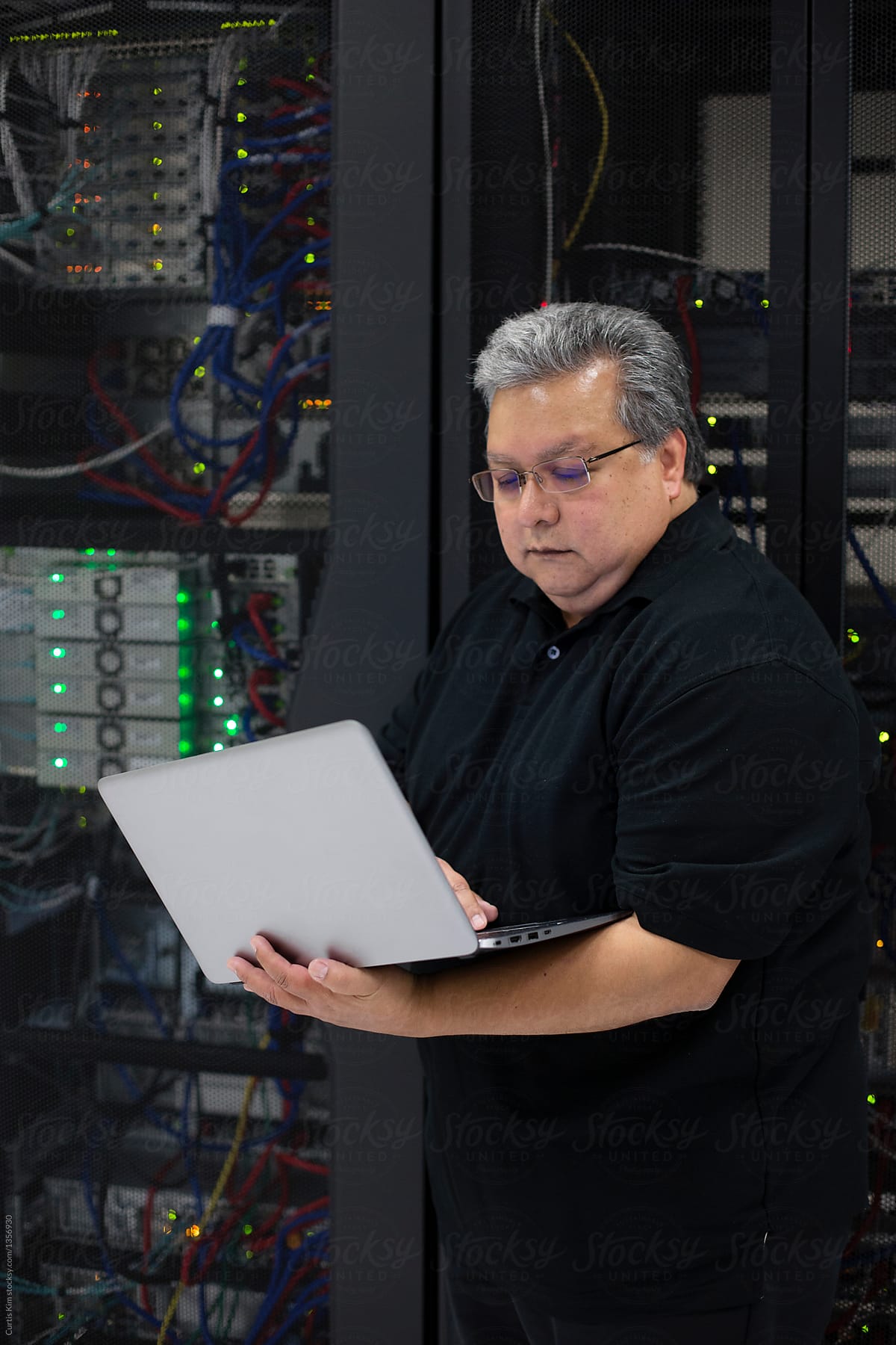 Computer expert working on laptop in data center