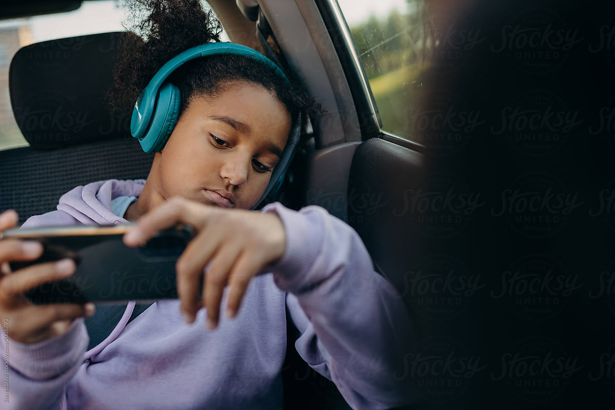Bored schoolgirl playing phone in car