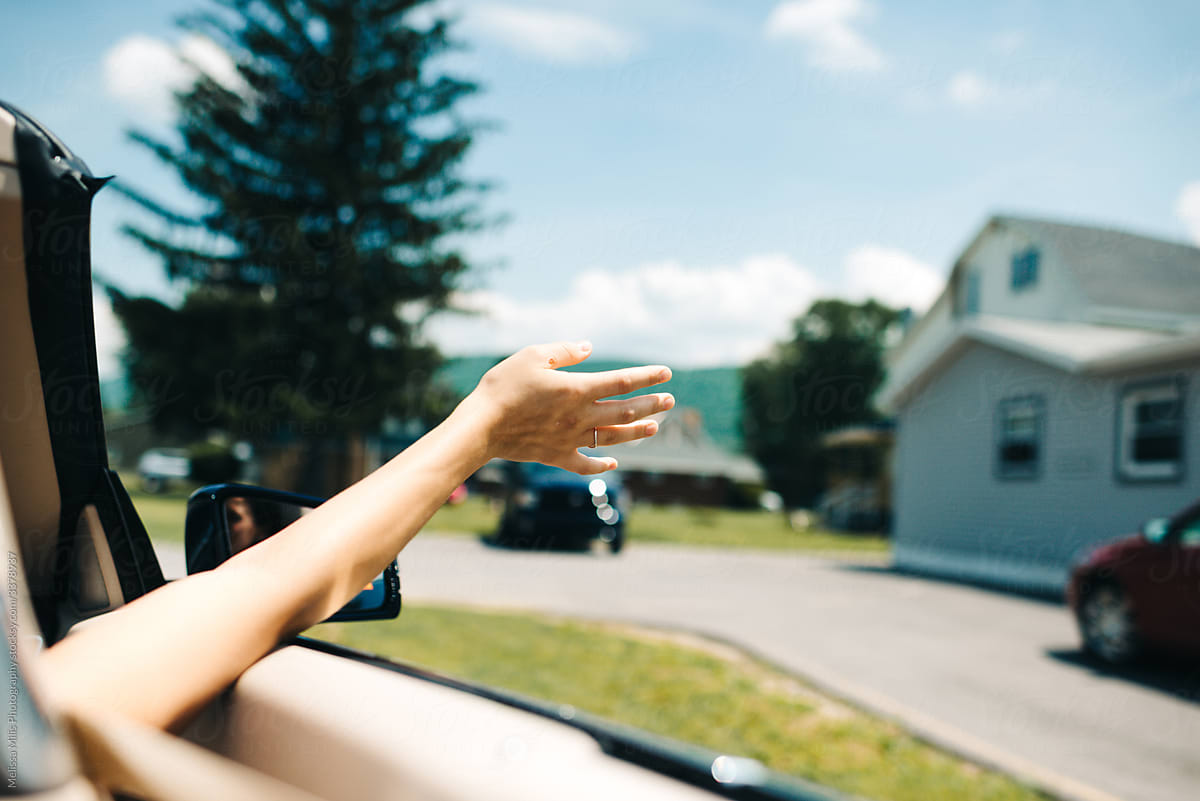 girl holding hands out of the car while driving free and wild