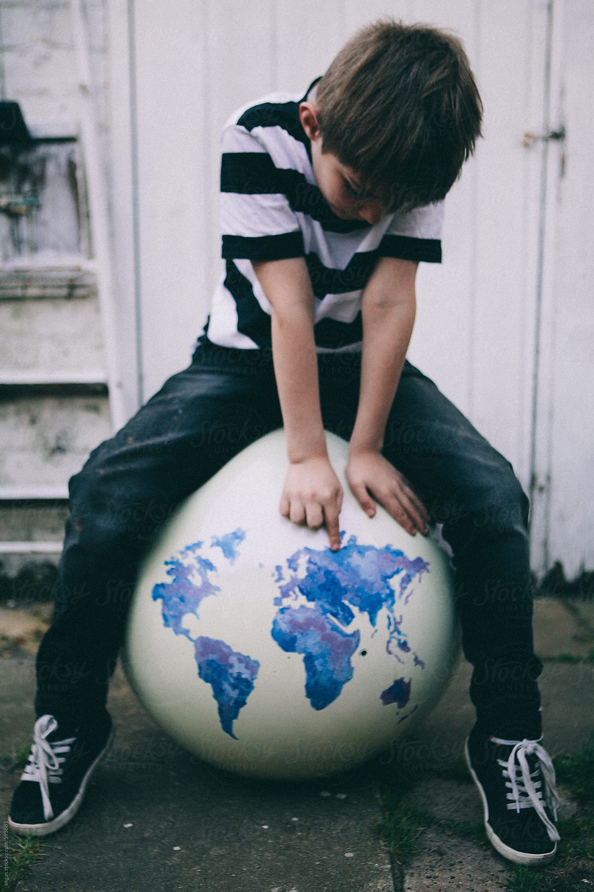 Young boy sitting on an oversized globe.