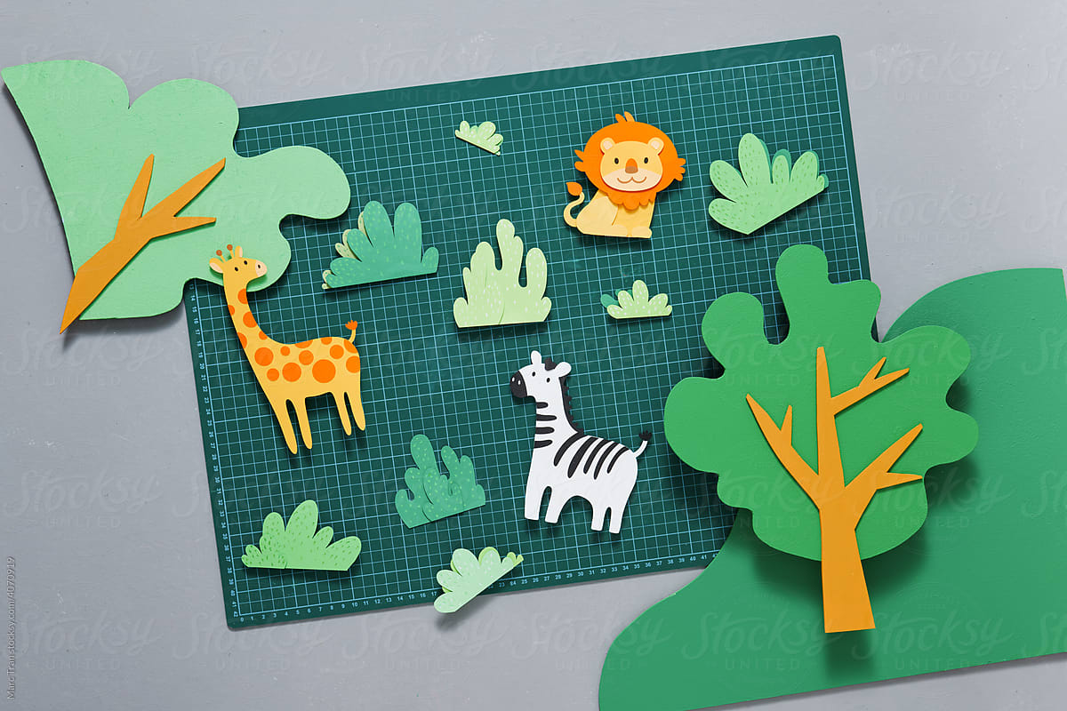 Papercraft with zebra, leon and trees on cutting mat