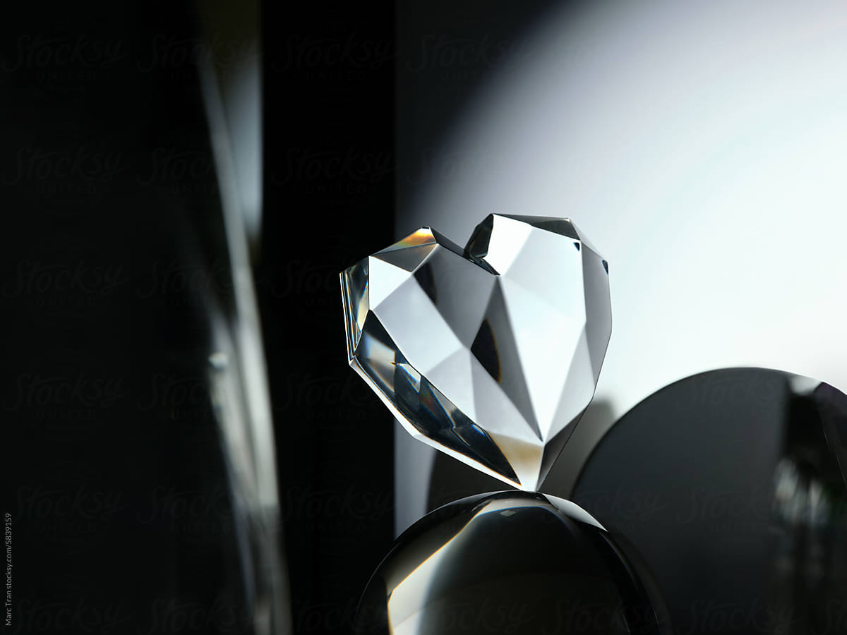Crystal heart balanced on glass ball in abstract background