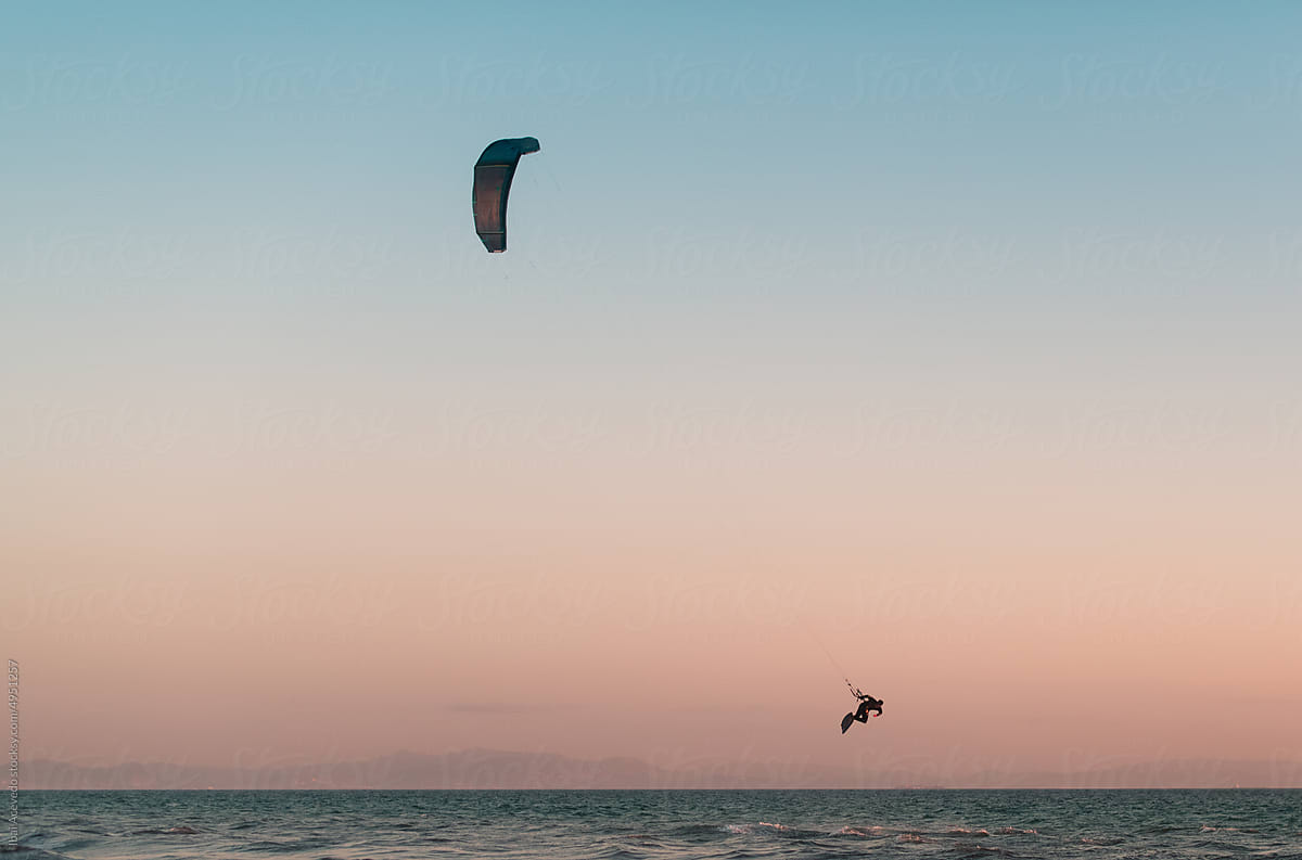 Flying kitesurfer during pastel sunset