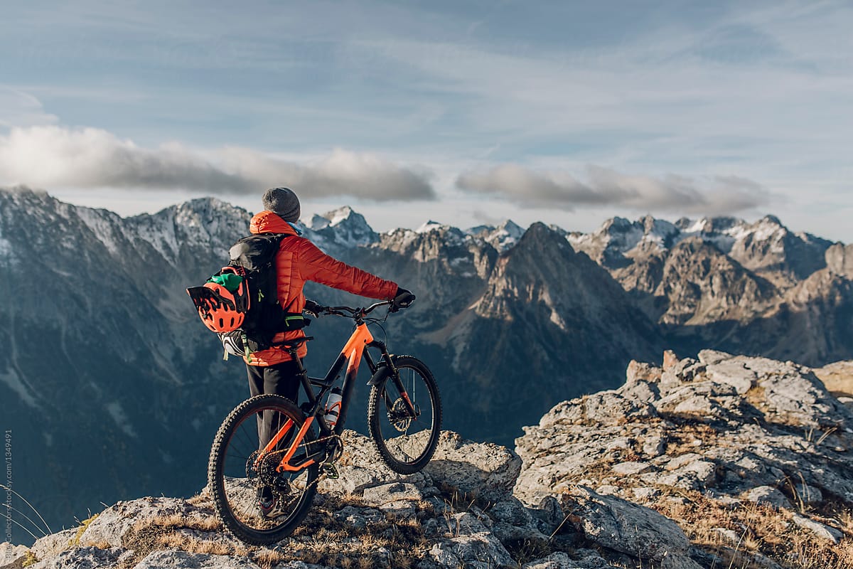 Young man looking the mountains with his mountain bike at the sunrise moment