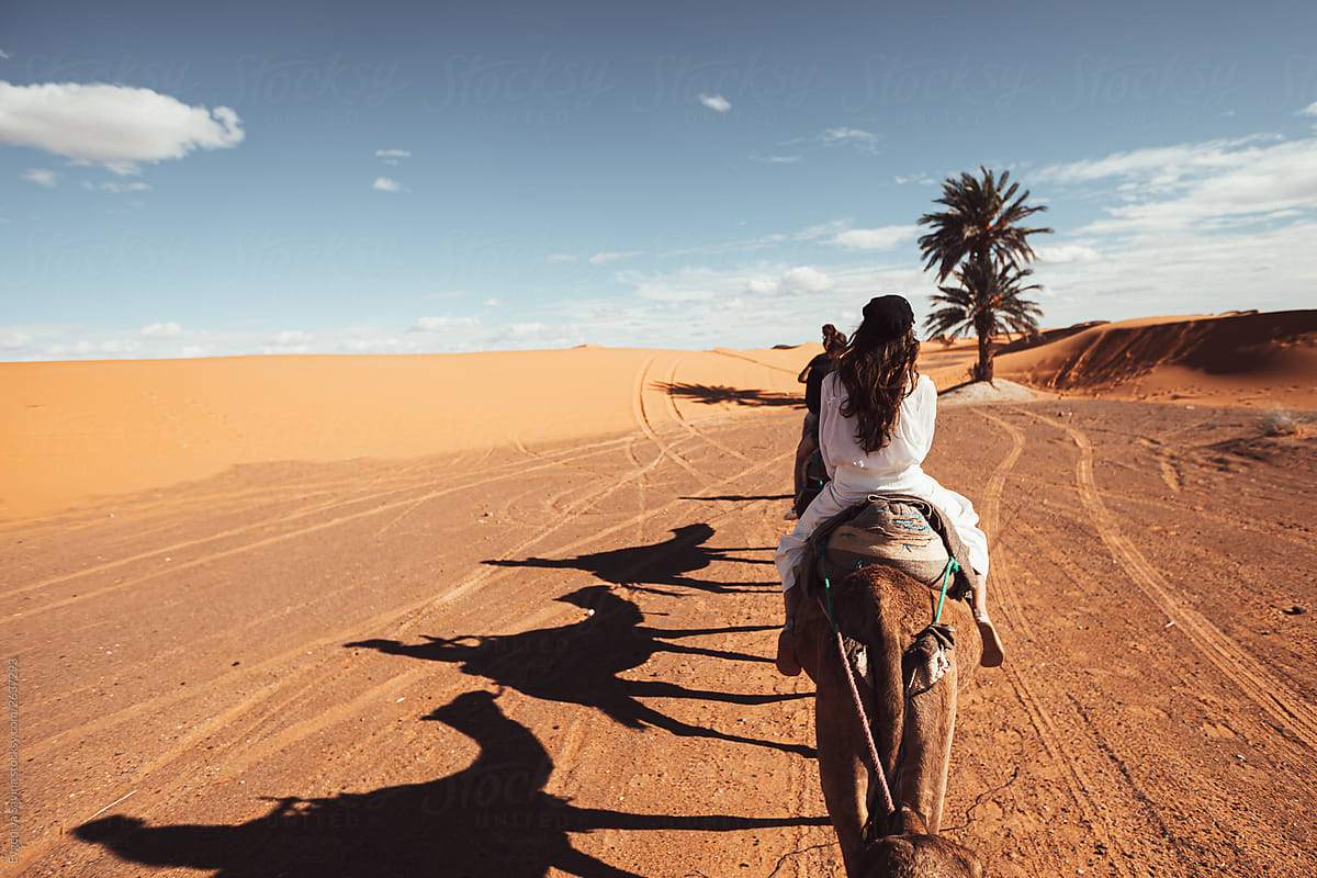 A girl im white clothes riding a camel