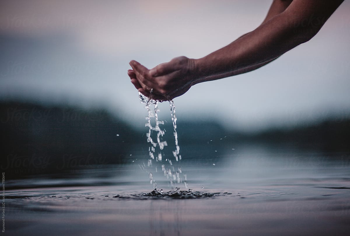 Holding Water in Hands at calm Lake landscape with water droplets