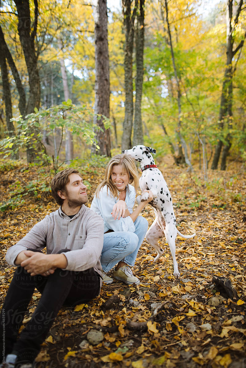 Hipster couple enjoying time with dog in autumn forest