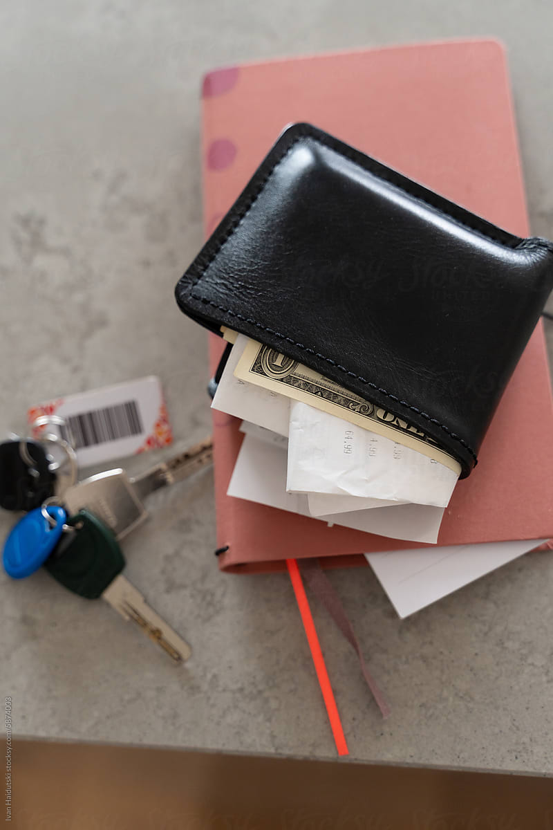 messy wallet with receipts and cash US dollars, notebook and keys
