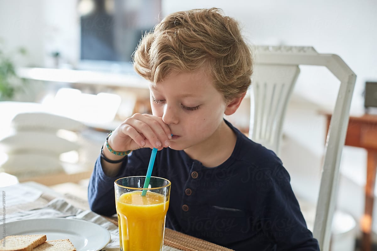 Happy child enjoying orange juice and breakfast at home