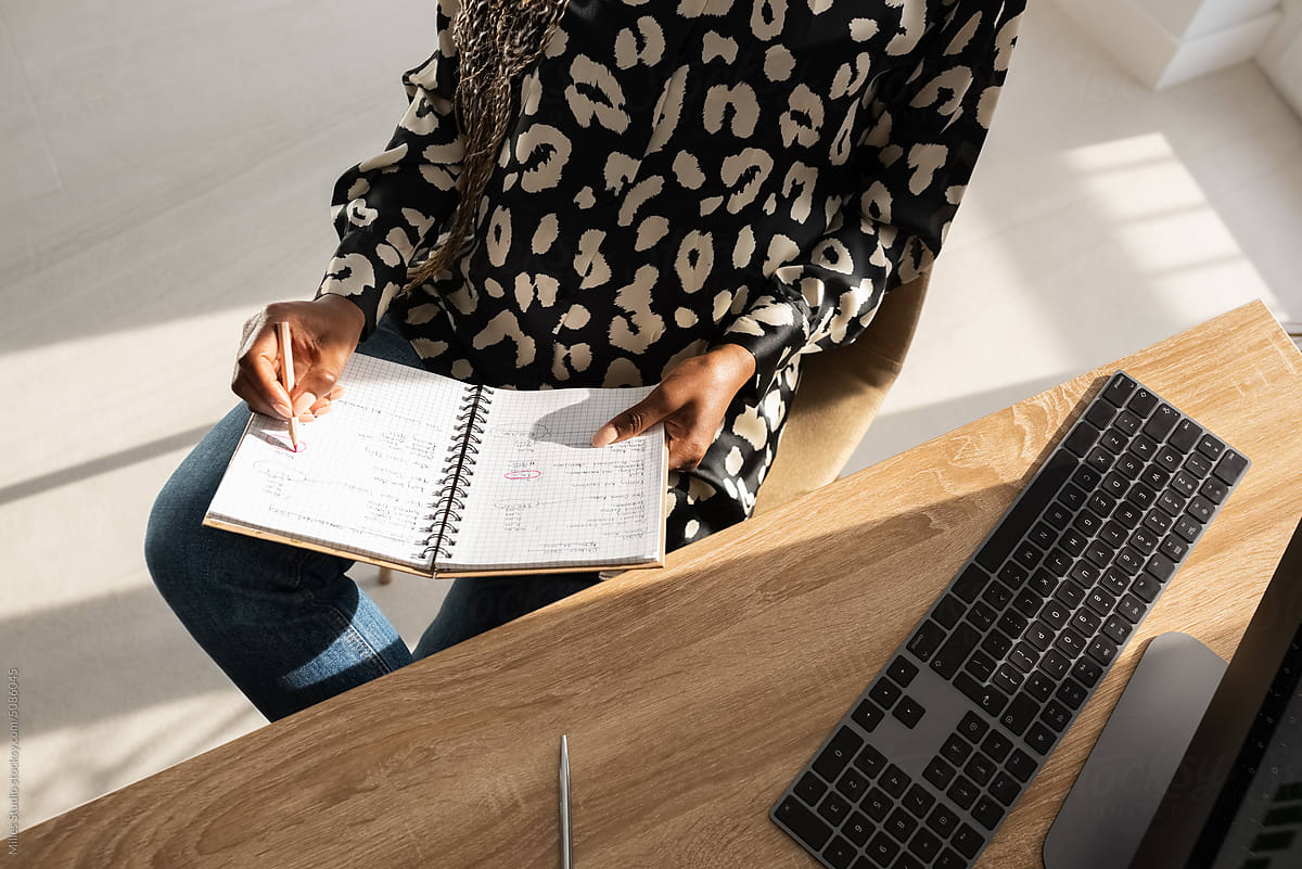 Crop pregnant businesswoman writing notes in notebook