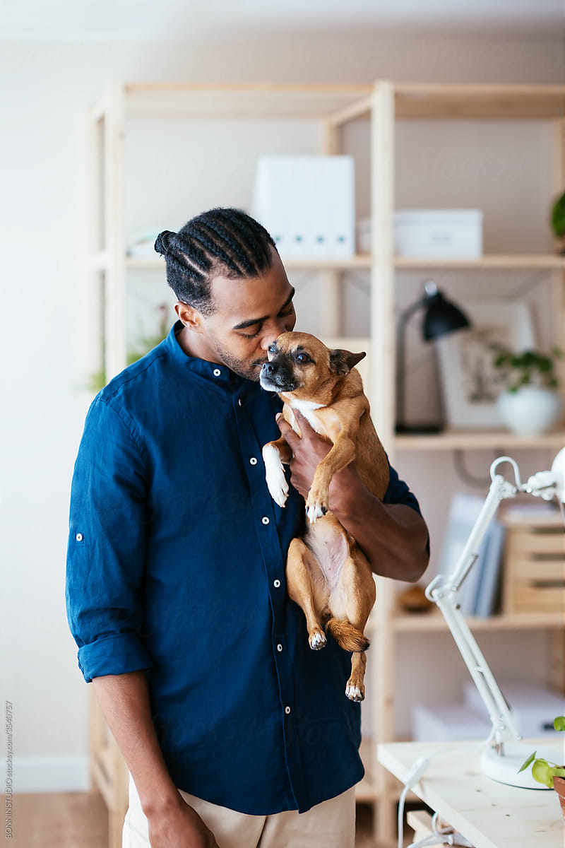 Ethnic man kissing dog in workplace