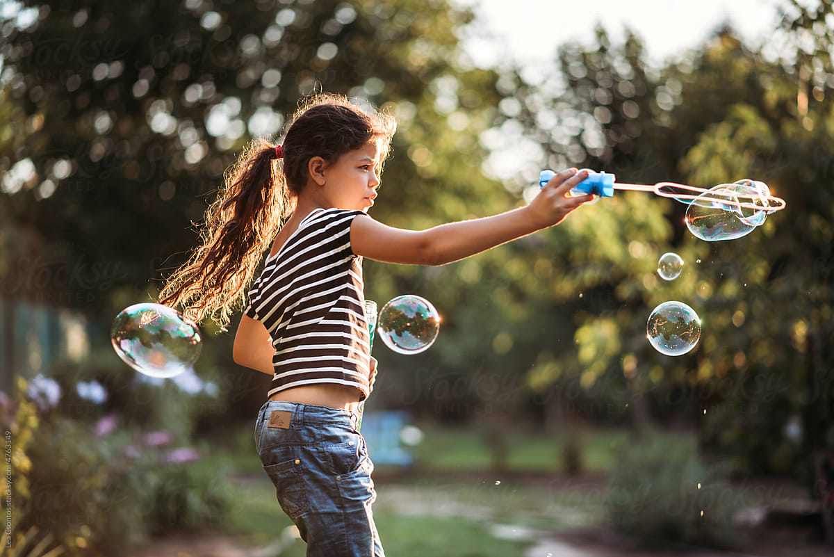 Young girl playing with a soap bubble wand