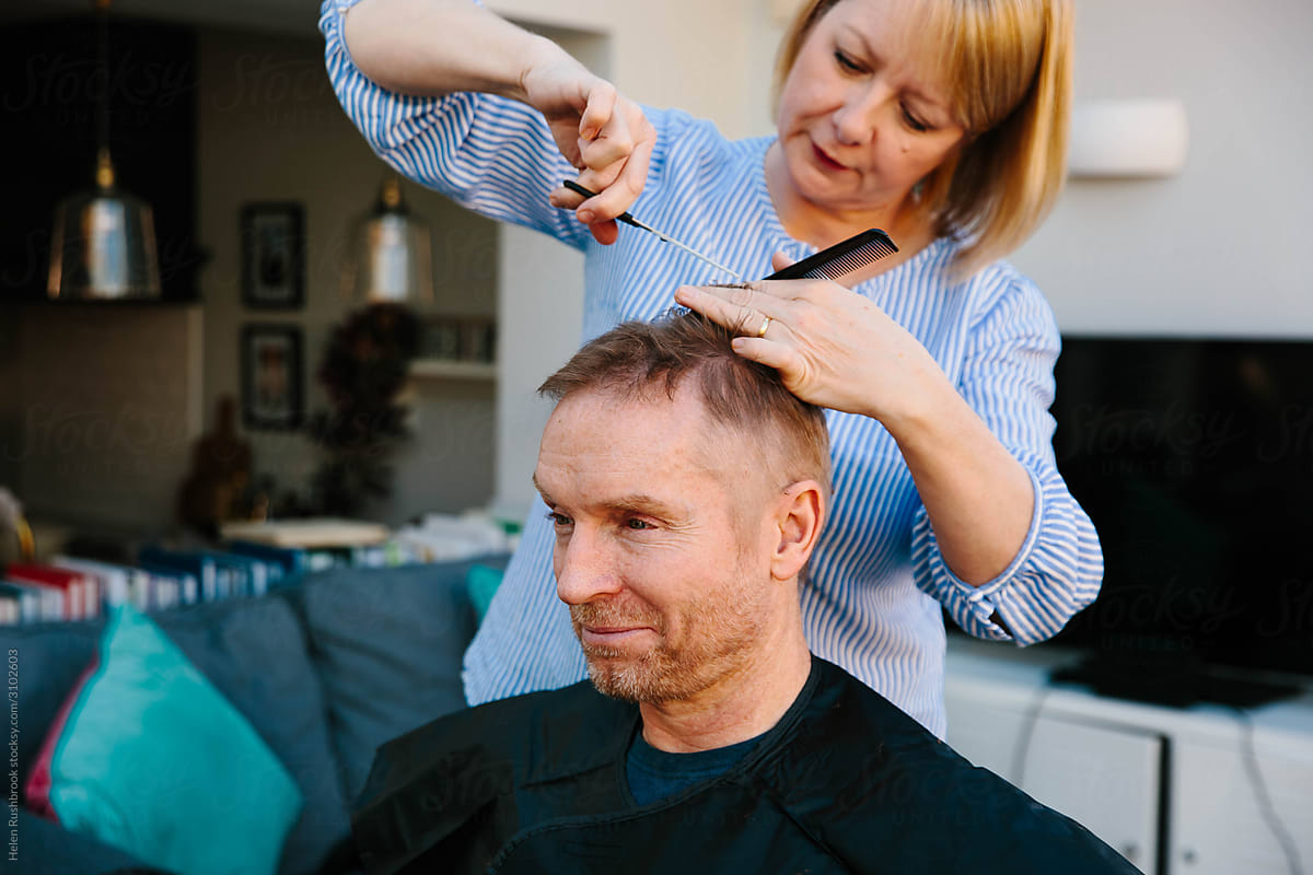 Woman cutting her husband\'s hair at home