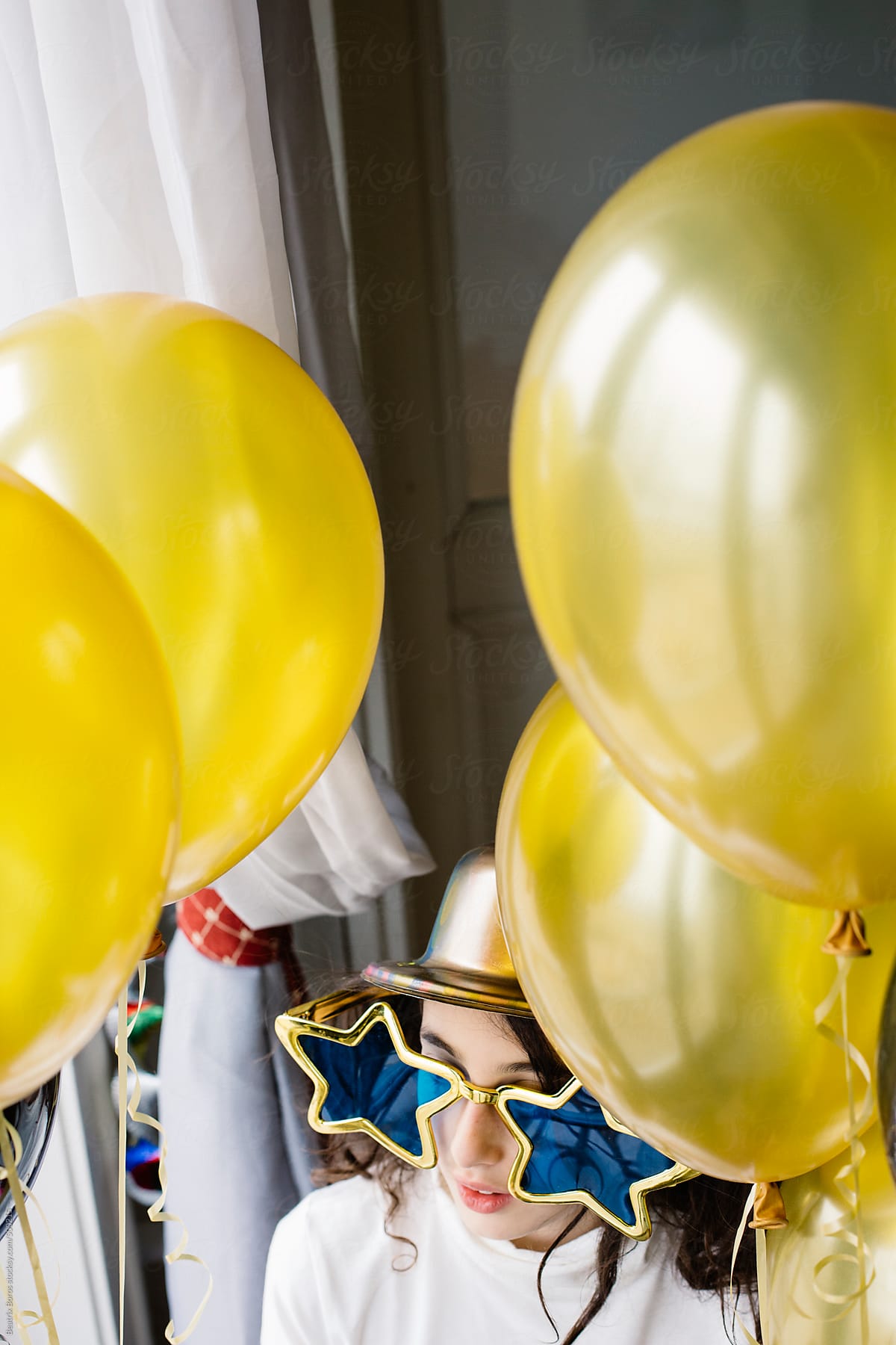 Vertical portrait of a girl at a party with balloons and sunglasses