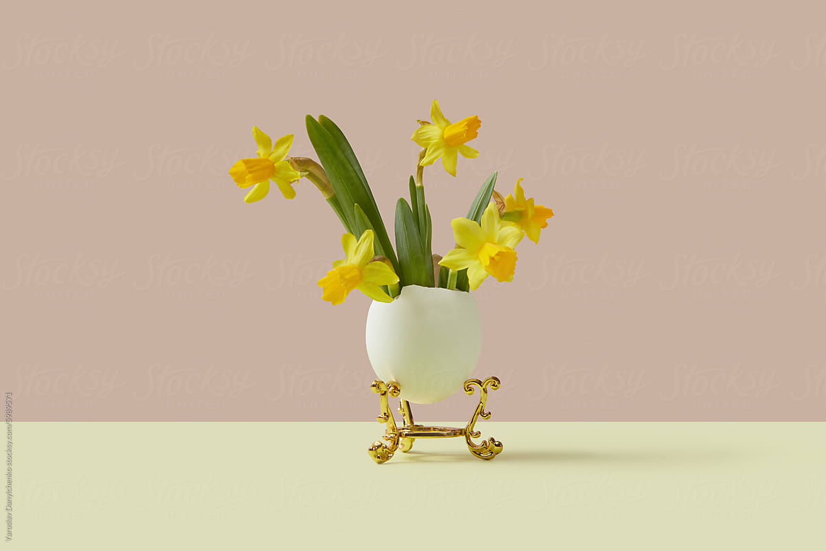 Bouquet of yellow daffodils in open egg leaning on golden rack