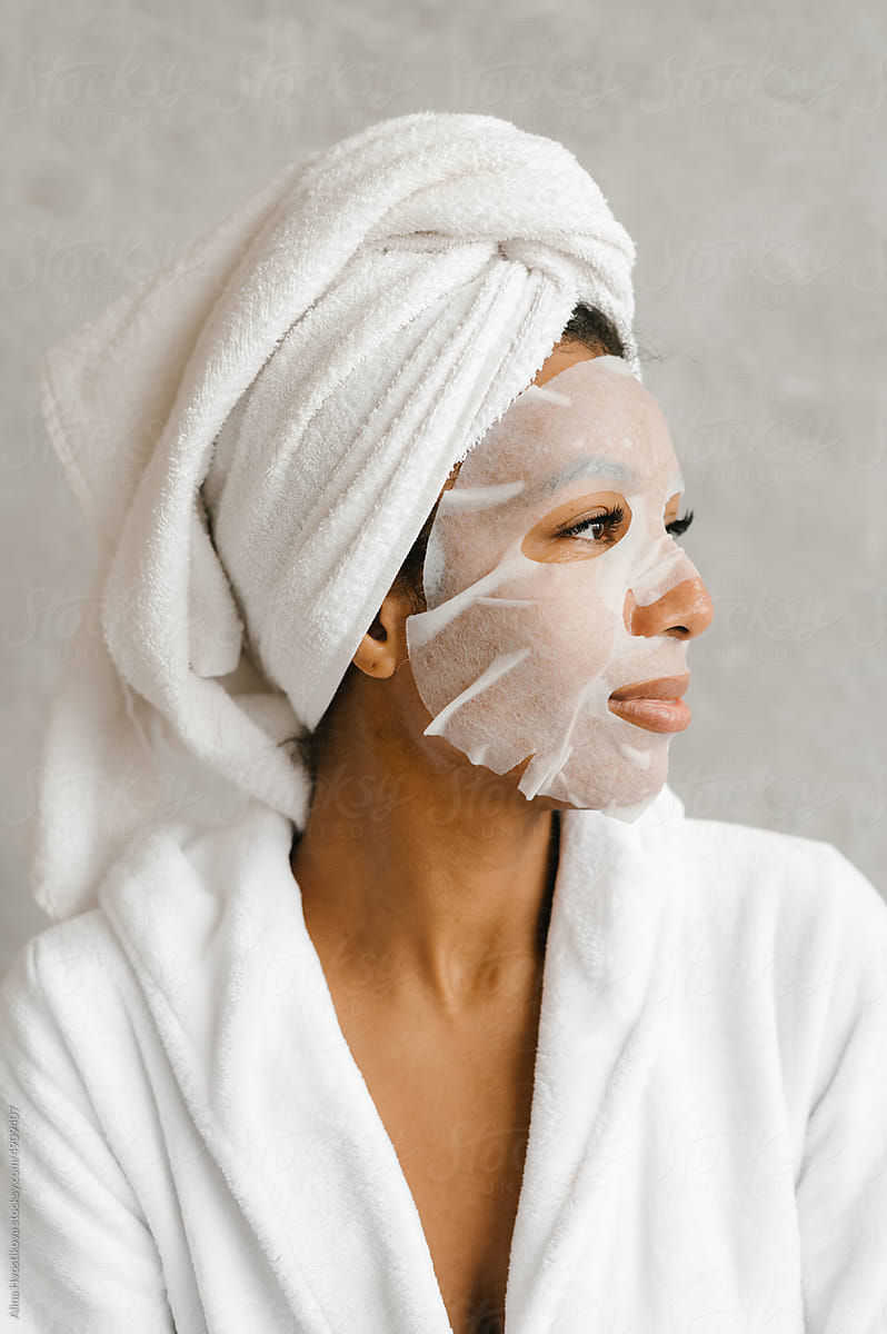 Young black lady with sheet mask looking away