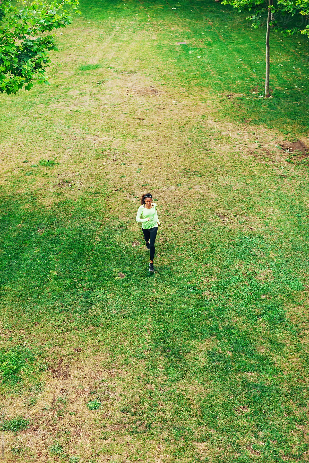 Woman Jogging In A Park Near The City by Stocksy Contributor MEM