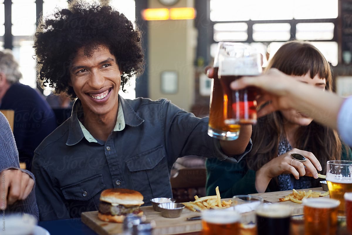 Afro hipster man cheers with beer