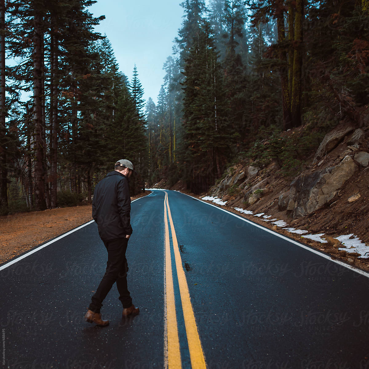 Young man walking down a mountain road