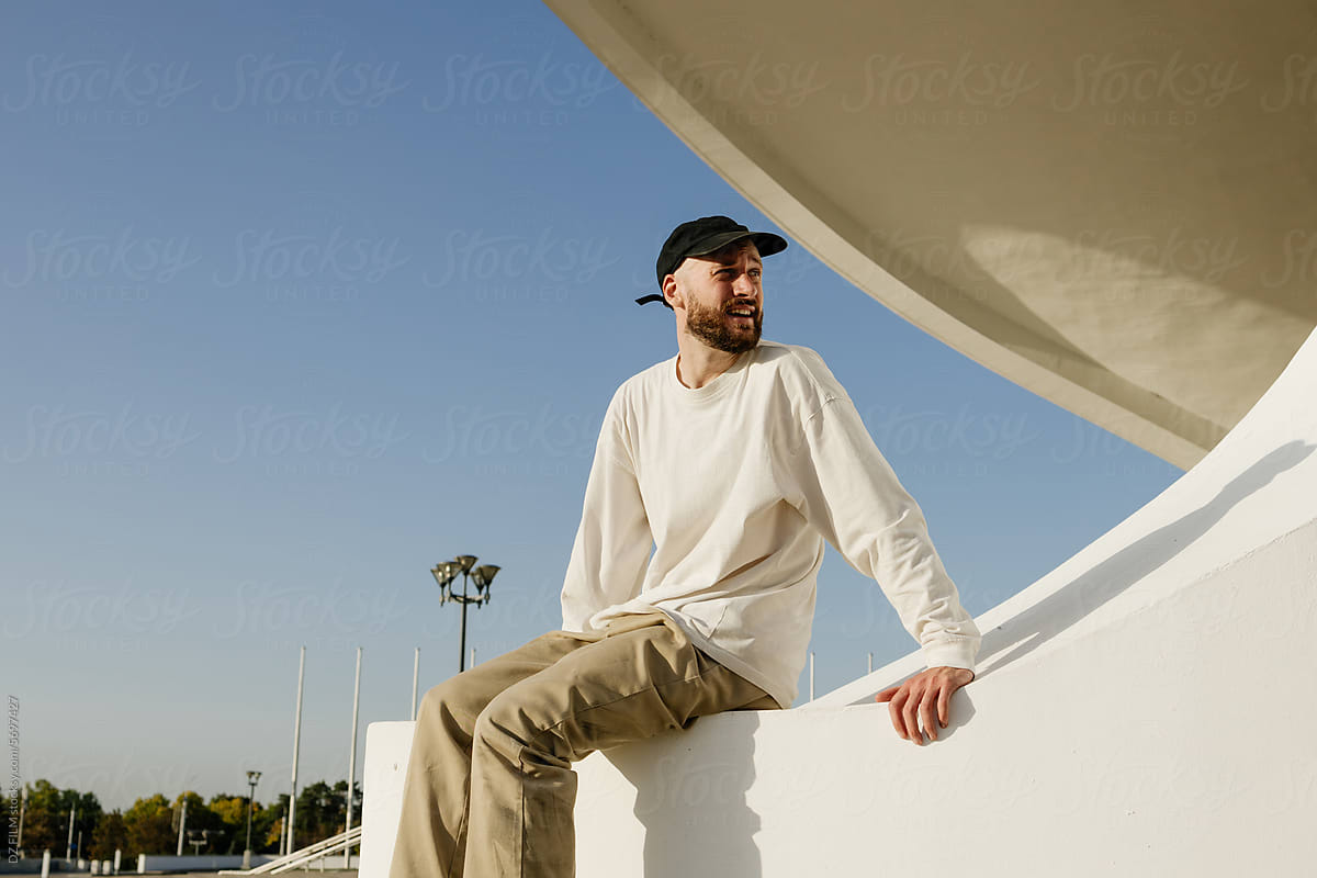 A man is sitting on the parapet of a city building