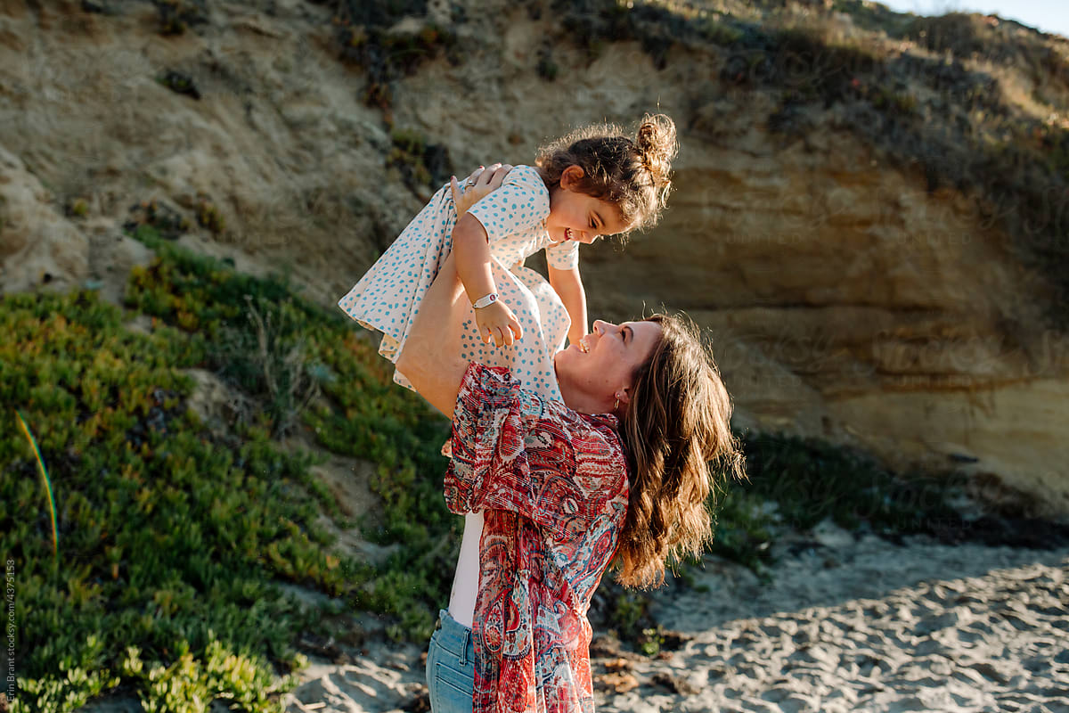 Mom lifts joyful daughter in the air