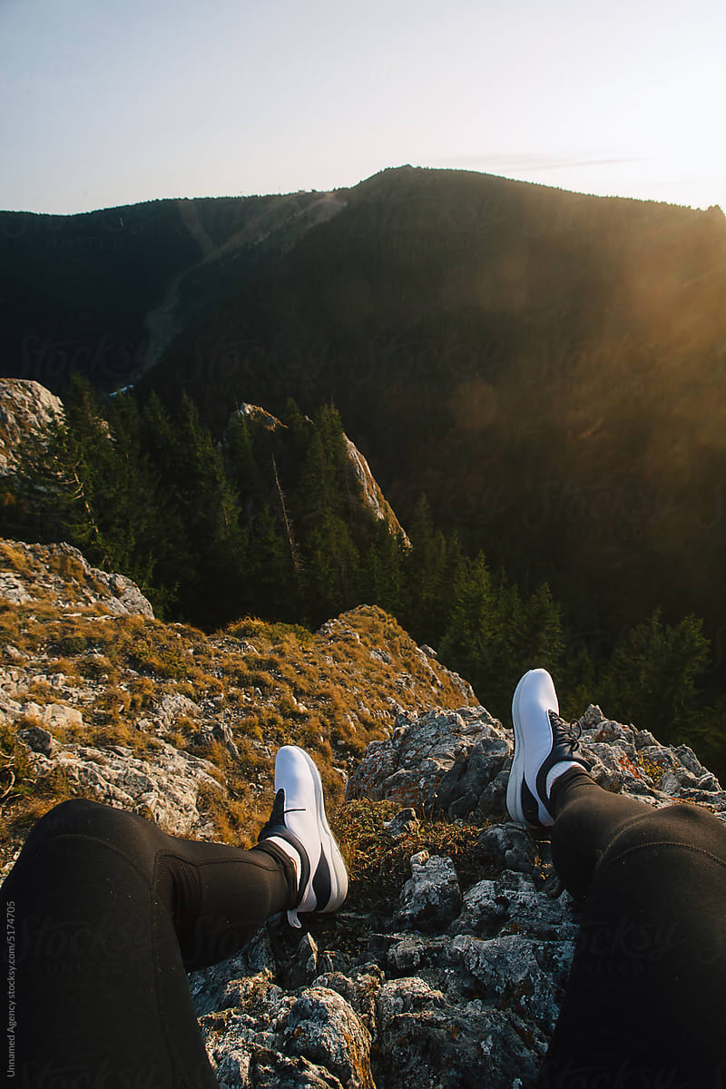 A man sitting on the cliff edge, Photo of legs dangling over the edge