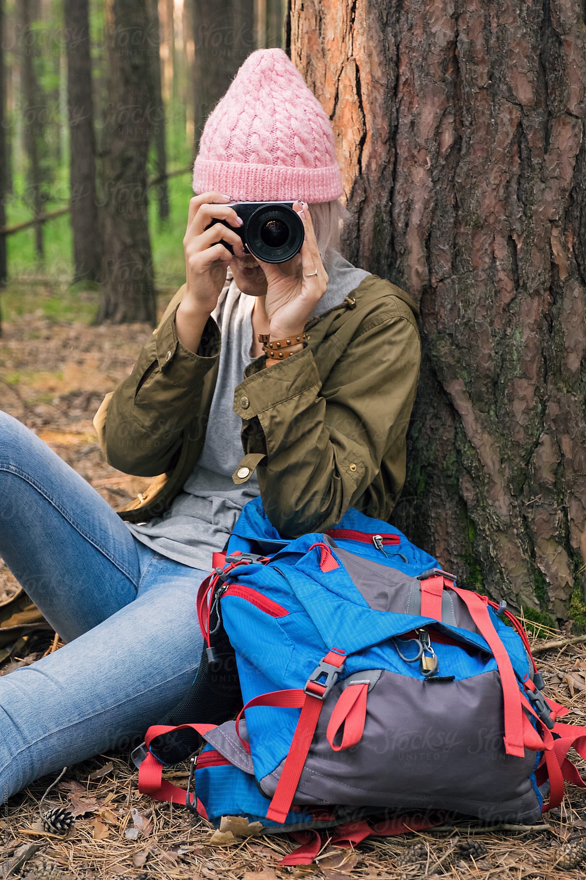 Young Girl Using Camera While Sitting Near Tree In Forest Del Colaborador De Stocksy Danil 
