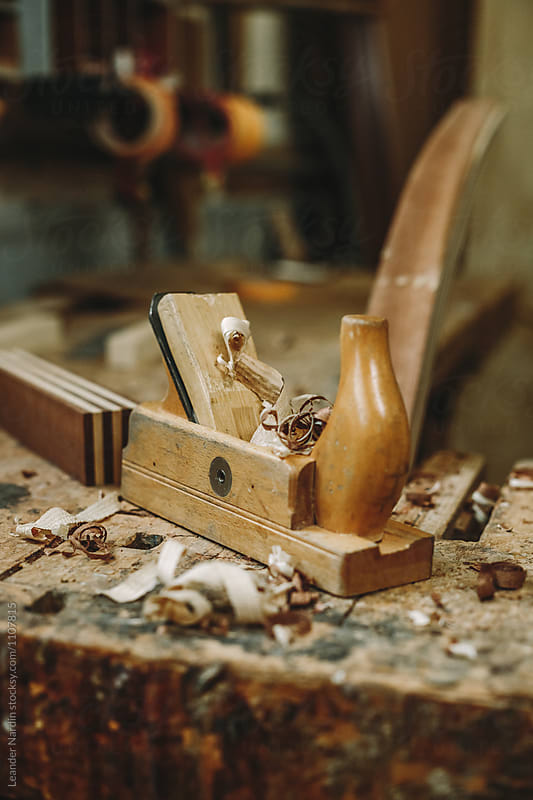 used wood plane with wood chips on wooden working bench